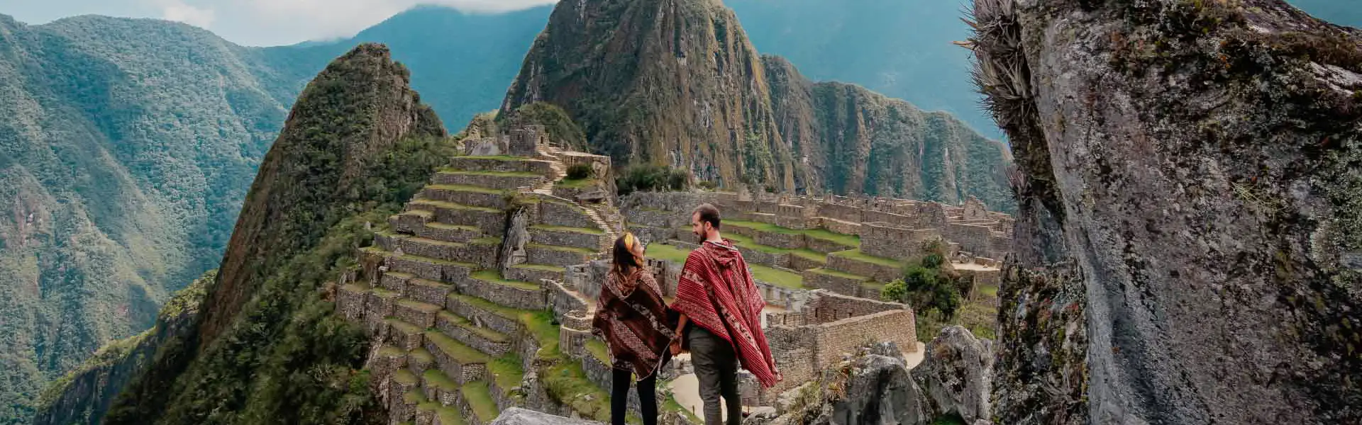 Pareja de turistas frente a la ciudadela de Machu Picchu en un día despejado